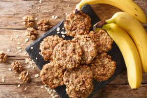 A plate of banana breakfast cookies next to 3 bananas